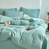 Light blue cotton yarn-dyed duvet cover with pillows and a book on a bed.