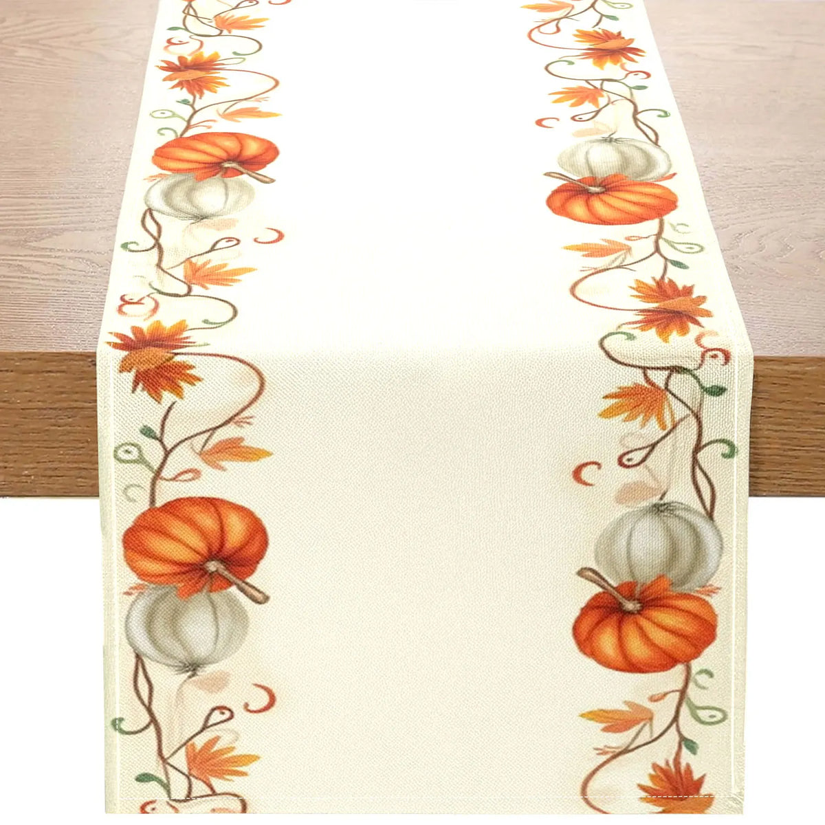 A cream table runner featuring an orange and green autumn harvest floral pattern.