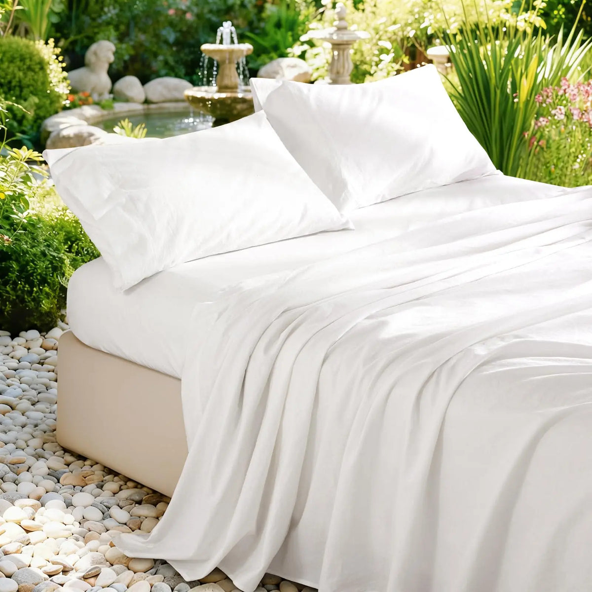 White pure French linen bed sheet draped over a bed in a lush garden setting.