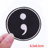 Black embroidered patch with white speech bubble symbol on a finger