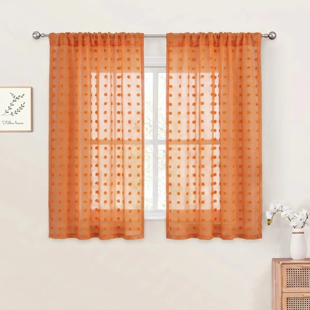 Orange pompom jacquard sheer curtain hanging in a window frame