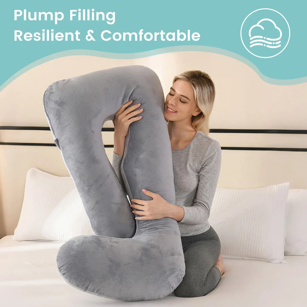 A woman is comfortably sitting on a gray J-shaped pillow designed for plump filling, in a bedroom setting.