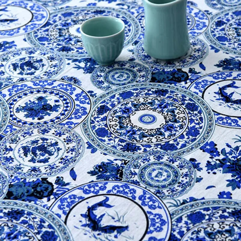 Blue and white patterned ceramic cups and plates on a white linen fabric