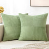 A set of four light green corduroy throw pillow covers with a vertical ribbed texture and patchwork design.