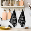 A set of two black absorbent kitchen cleaning towels with white text featuring the phrase The itch is the heart of the home