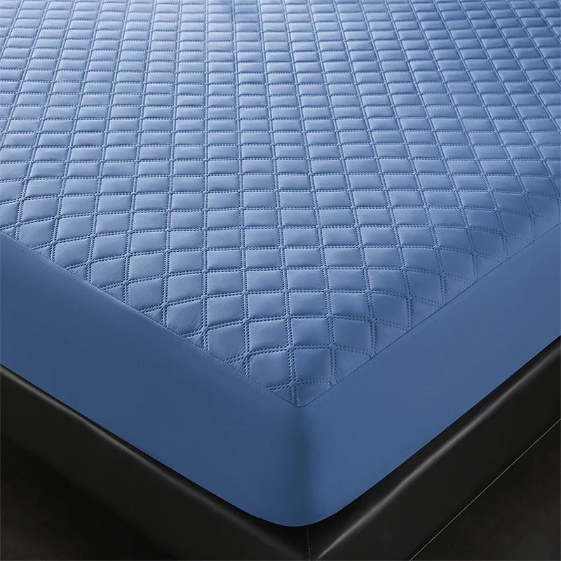 A close-up view of a blue quilted mattress protector placed on a black mattress.