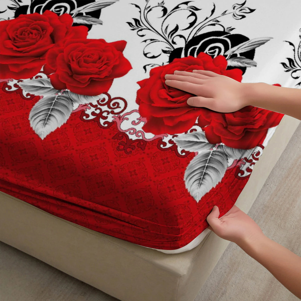 A hand gently touches a vibrant red rose pattern on a fitted mattress cover.