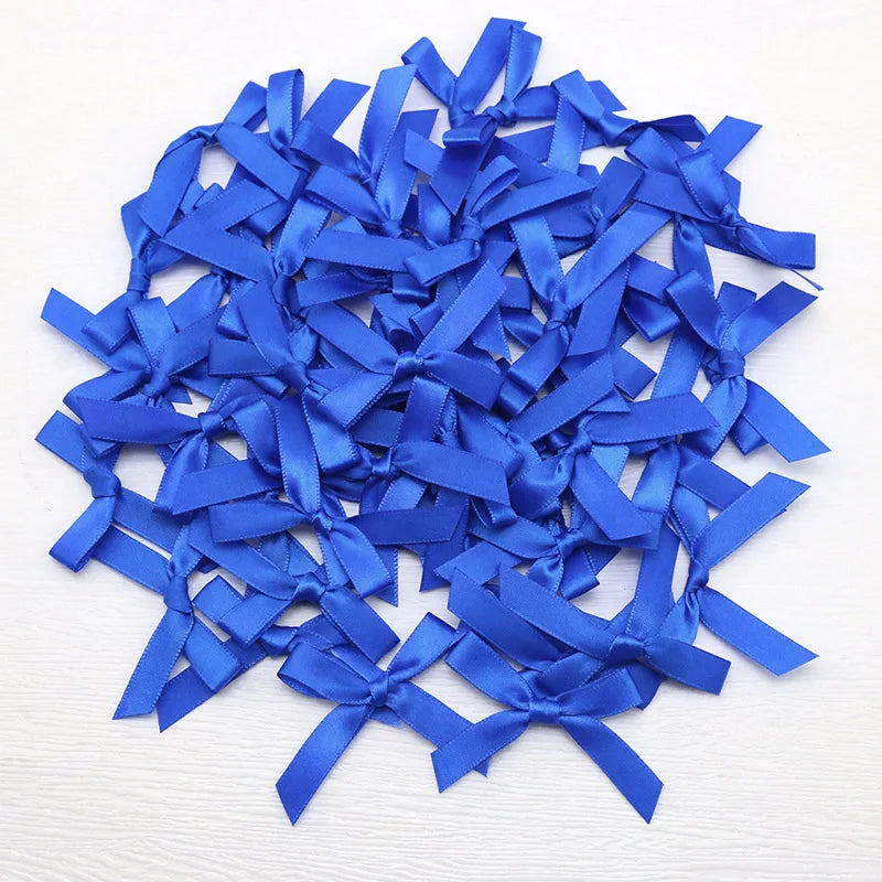 A pile of small royal blue satin ribbon bows for crafts and decor.