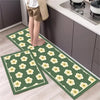 Two green diamond print non-slip kitchen rugs are displayed on a light wood floor next to dark cabinets.