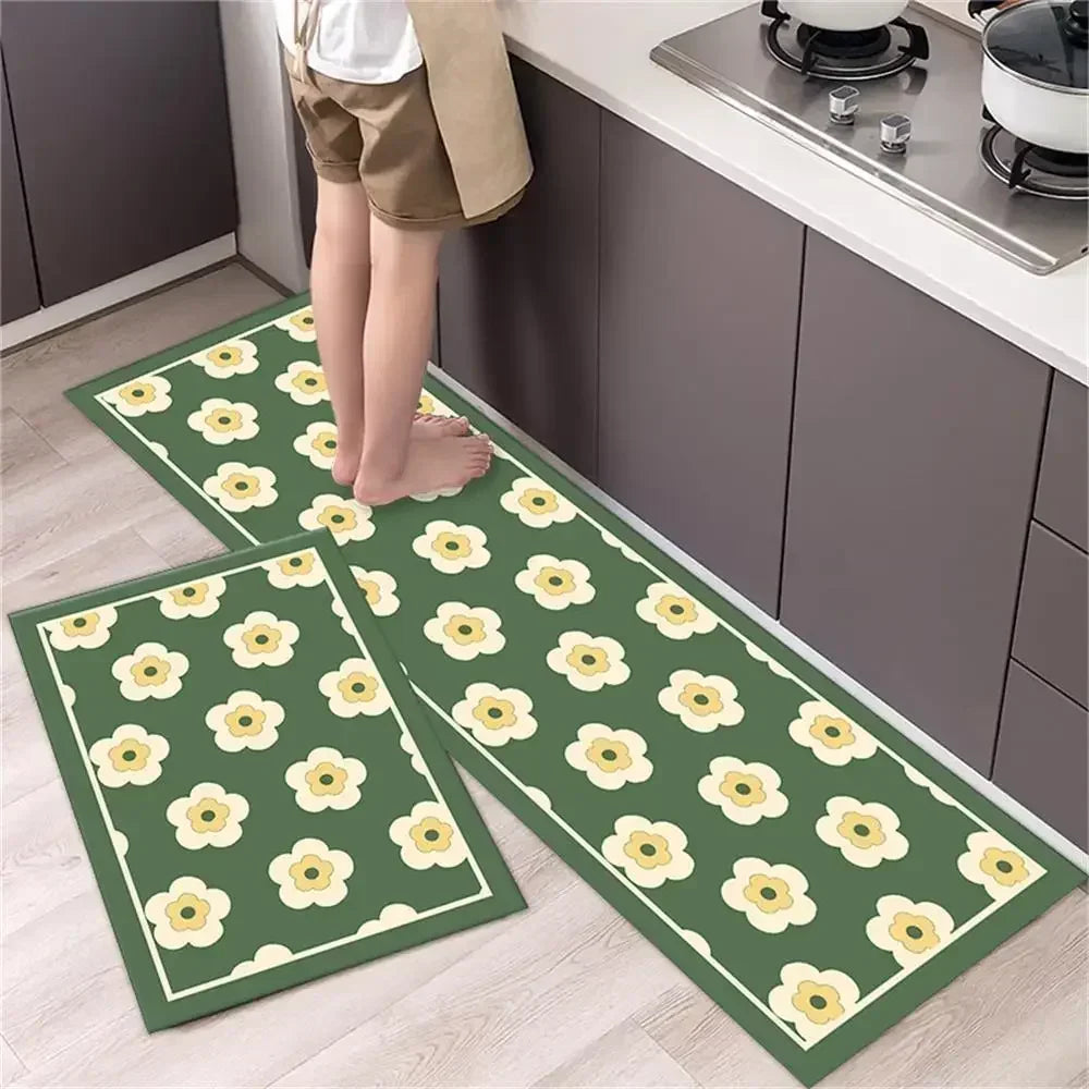 Two green diamond print non-slip kitchen rugs are displayed on a light wood floor next to dark cabinets.