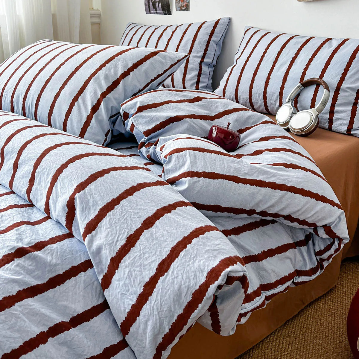 A bed covered with a striped duvet and pillow set featuring white and brown stripes.