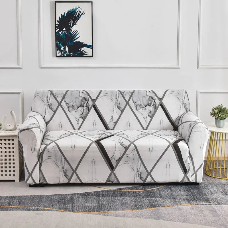 A white stretch floral elastic sofa cover displayed on a light gray floor with framed artwork in the background.
