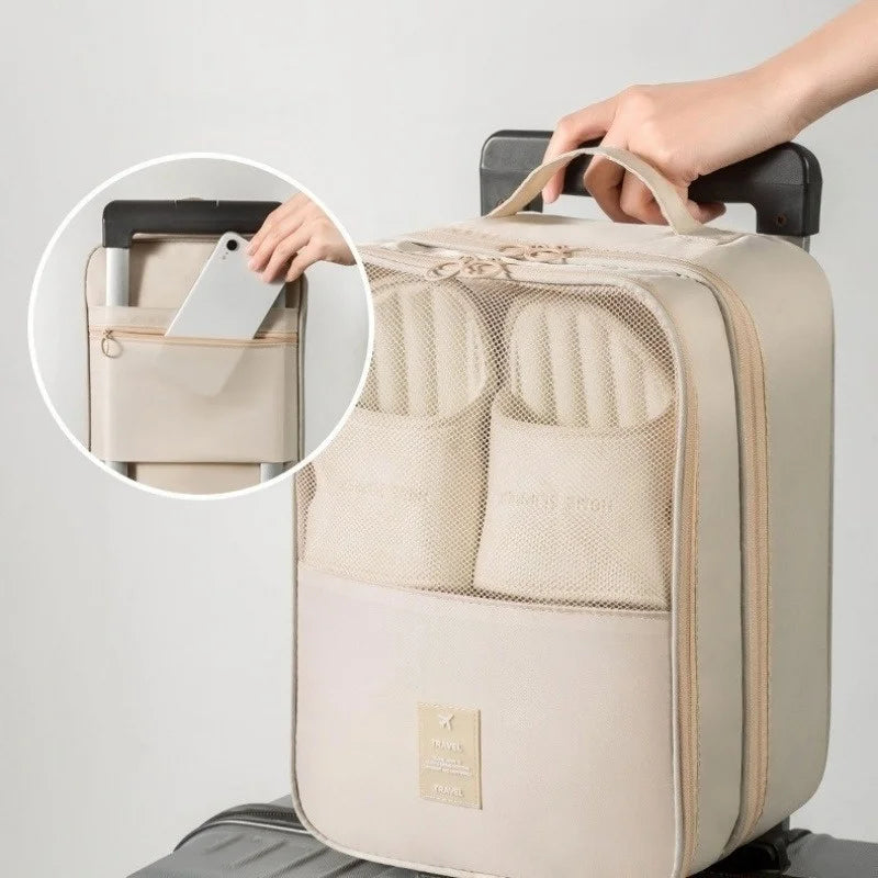 A beige portable travel shoe organizer bag with multiple internal compartments is shown being held by a hand.