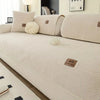 A cream sherpa anti-slip sofa cover with light beige cushions and decorative knit accents.