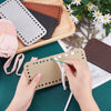 Hands are assembling a set of four square woven bag hanging hooks in various earth tones on a wooden board.