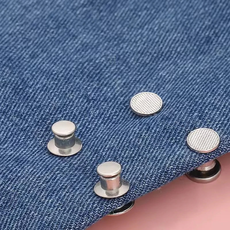 Close-up of metal button snaps on a blue denim fabric.