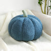 A fuzzy, blue Nordic-style pumpkin plush decoration resting on a white fabric surface.