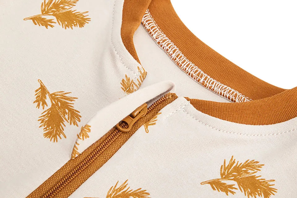 Close-up of a white soft cotton baby sleeping bag with gold leaf pattern and a tan collar.