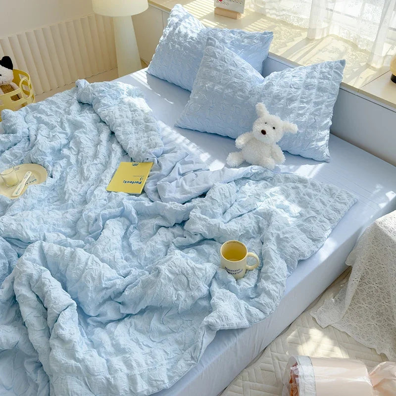 Light blue summer seersucker quilt comforter with fluffy pillows and a yellow tag