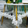White lace embroidered PVC tablecloth draped over a gold-framed glass table.