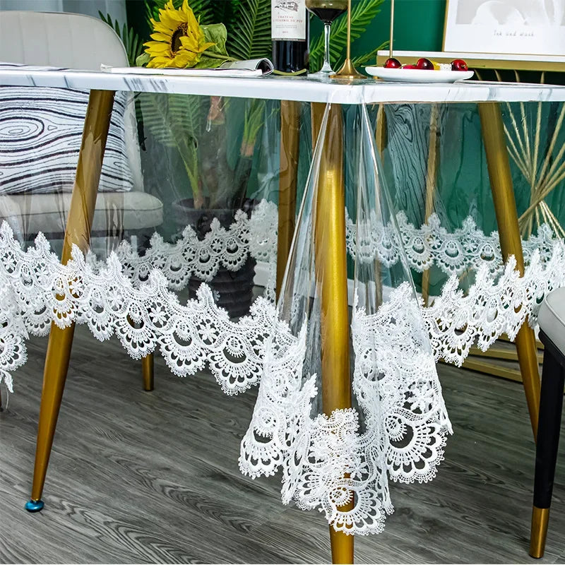 White lace embroidered PVC tablecloth draped over a gold-framed glass table.