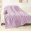 A soft lavender checkered fleece throw blanket draped over a white sofa.