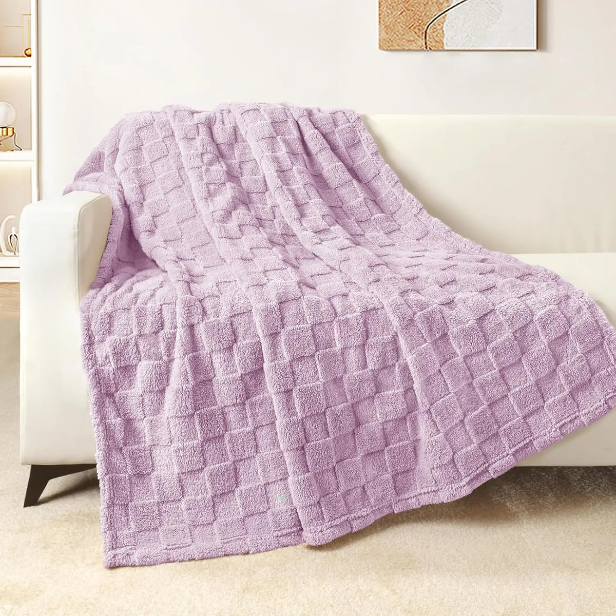 A soft lavender checkered fleece throw blanket draped over a white sofa.