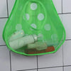 A bright green mesh bath toy organizer filled with various bath toys and featuring adhesive hooks.