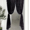 A pair of dark gray floral lace sheer rod pocket curtain panels hanging in a white doorway.