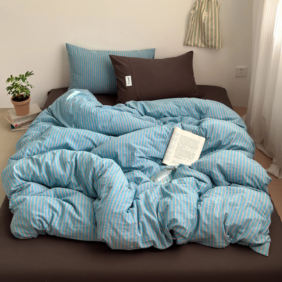 A blue and white striped cotton duvet cover set with a dark brown pillow on a bed.