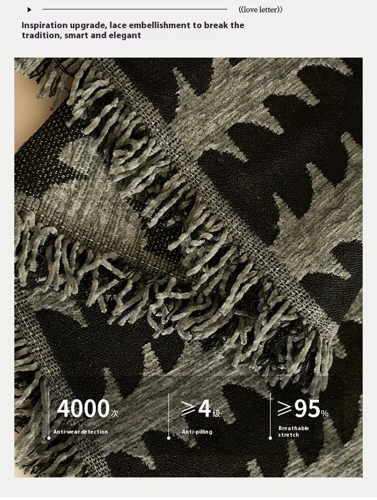 Close-up of a dark gray herringbone chenille sofa cover featuring textured fabric and tassel fringes.