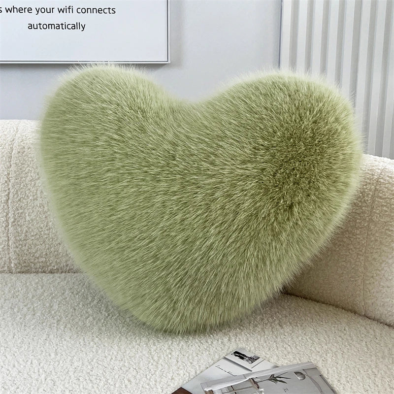 A soft, light green heart-shaped throw pillow made of fluffy fox fur resting on a white sofa.