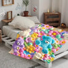 A colorful flannel blanket featuring a floral print with various stuffed animals like bears and flowers.