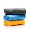 A stack of three coral fleece microfiber cleaning cloths in gray, blue, and yellow.