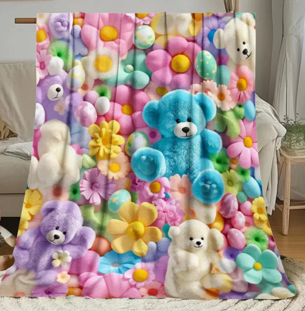 A colorful flannel blanket featuring a floral print with various teddy bears and pastel colors.