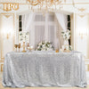 Silver sequin glitter tablecloth draped on a table in an elegant room with a window and chandelier.