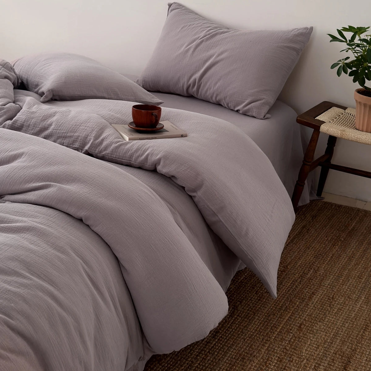A gray duvet cover set with a matching pillow and a small wooden bowl on a bed.