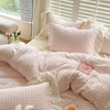 A pink gingham duvet cover set with matching pillowcases and a white border displayed on a bed.