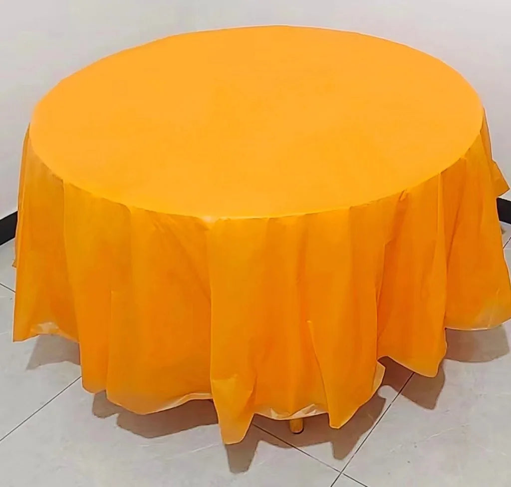 A round, bright orange plastic disposable table cover spread on a white surface.