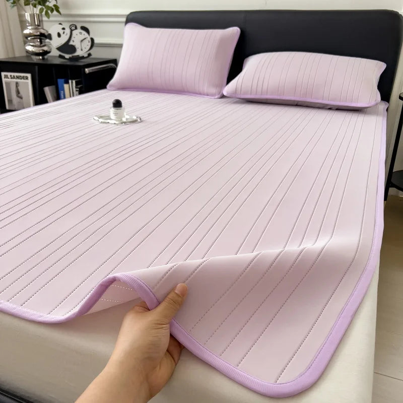 A hand is folding a pink cooling ice silk bed pad on a bed.