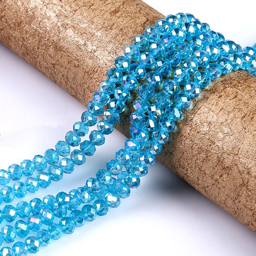 A strand of bright blue faceted rondelle glass beads is coiled on a brown cylindrical object.