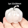 A smooth, translucent pink natural stone pumpkin figurine with a silver stem is held in a hand.