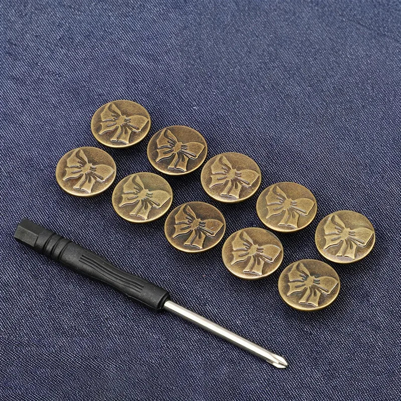 A set of ten antique brass snap buttons arranged in a line on a dark blue fabric background.