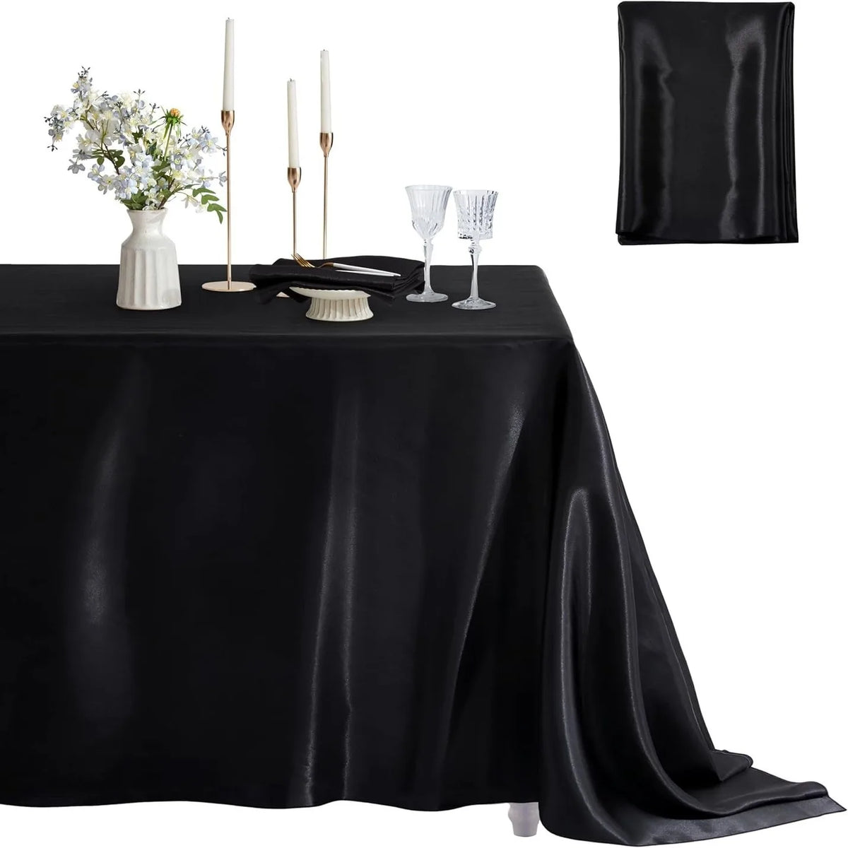 Black satin tablecloth set featuring candles, silverware, and a white floral arrangement for elegant dining decor