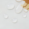 Several clear, round droplets of liquid are scattered on a white fabric surface.