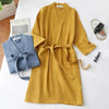 A mustard yellow cotton terry robe with a tie belt is displayed on a white surface.