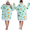 A woman models a light mint green patchwork fleece hoodie with various fruit and leaf patterns.