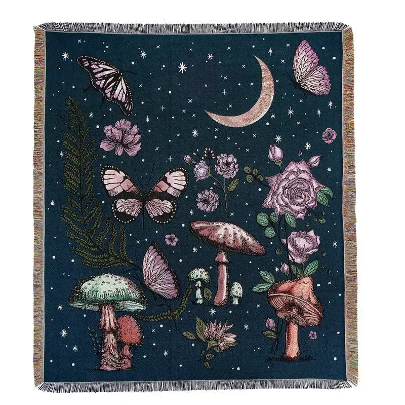 A dark blue throw blanket featuring a botanical and celestial design with moths, roses, mushrooms, and a crescent moon.