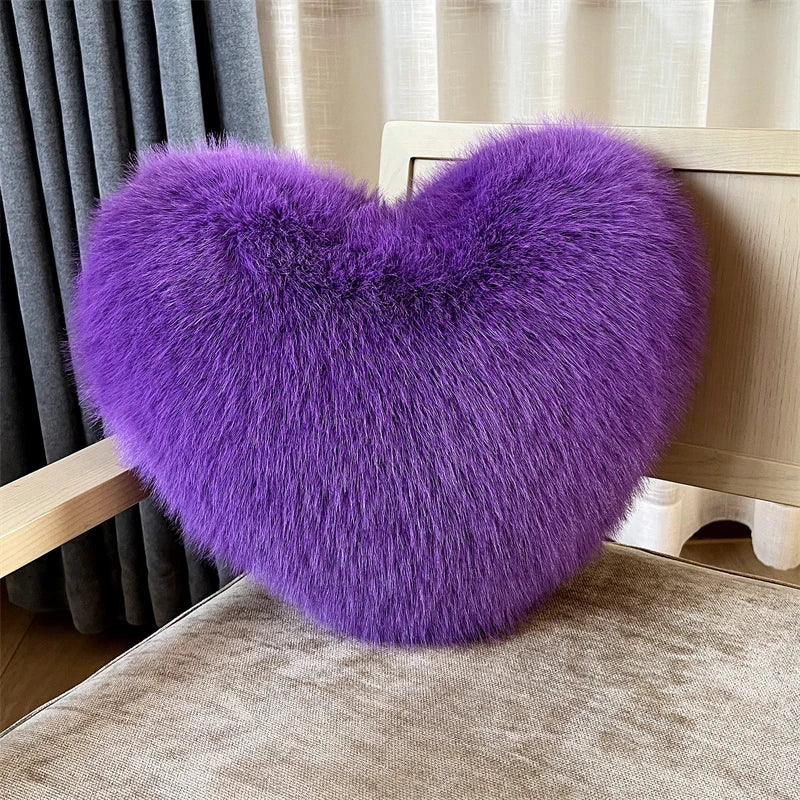 A vibrant purple plush heart-shaped fox fur throw pillow resting on a light wooden surface.