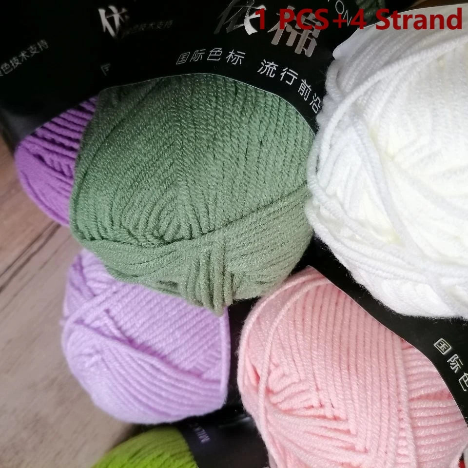 A close-up of various skeins of organic cotton 4ply knitting yarn in shades of green, purple, and pink.